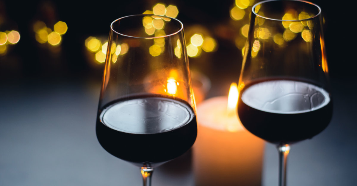 Two glasses of wine in front of lit candles