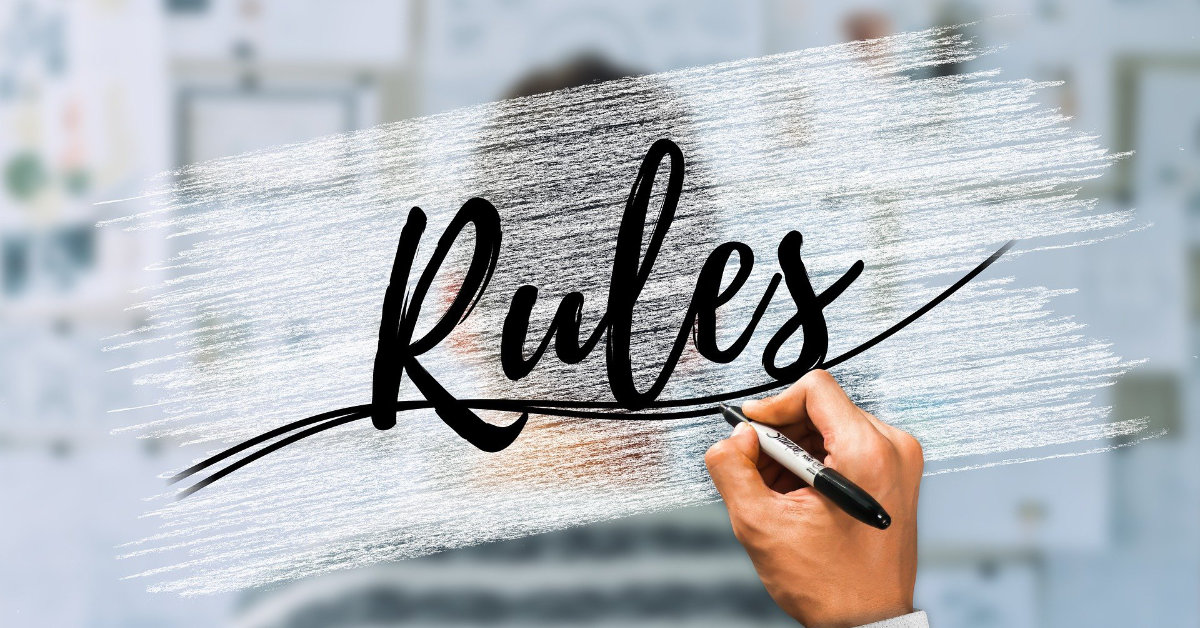 A hand writing "Rules" on a glass background