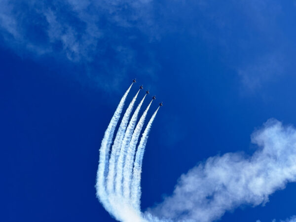 Five jets flying side-by-side as they do a loop in a very blue sky.