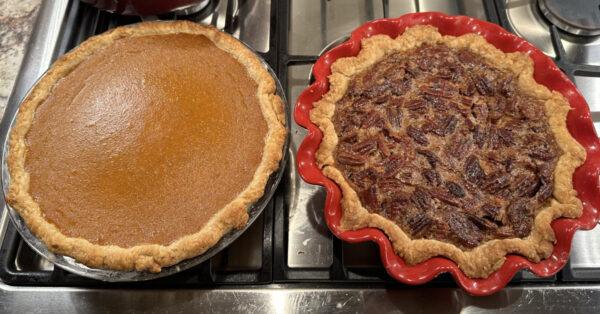 A pumpkin and pecan pie cooling on the stove.